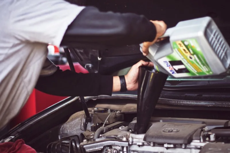 Mechanic topping up engine oil during a car service